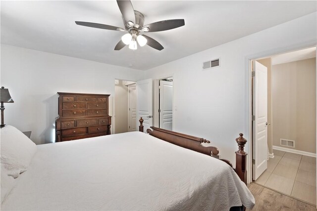 bedroom with visible vents, light wood-style flooring, ensuite bathroom, and ceiling fan