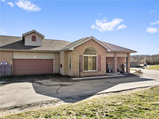 view of front of home featuring aphalt driveway, brick siding, an attached garage, and a shingled roof