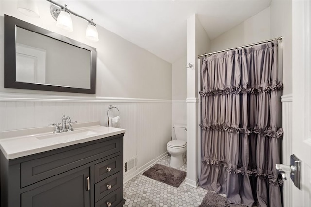 full bathroom with visible vents, a wainscoted wall, toilet, vaulted ceiling, and vanity