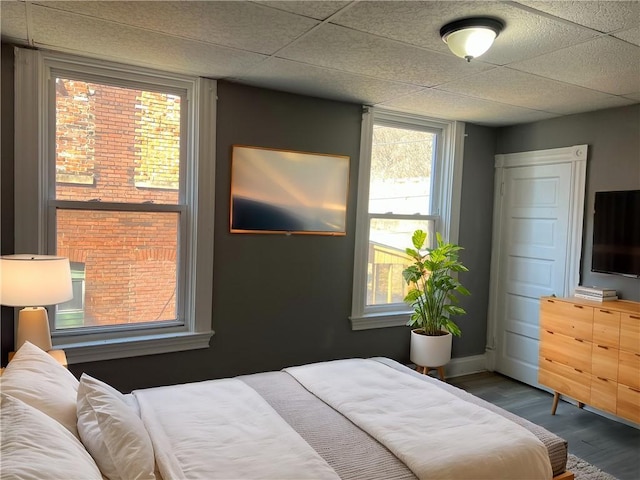 bedroom with a drop ceiling and wood finished floors