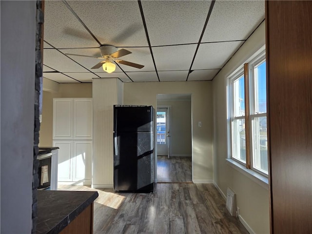 interior space featuring dark countertops, visible vents, dark wood finished floors, a drop ceiling, and freestanding refrigerator