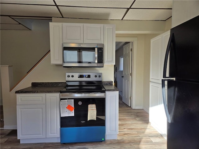 kitchen with dark countertops, white cabinets, a paneled ceiling, and appliances with stainless steel finishes