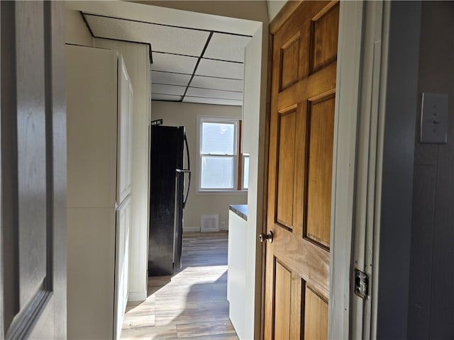 corridor featuring baseboards, visible vents, a drop ceiling, and light wood-type flooring