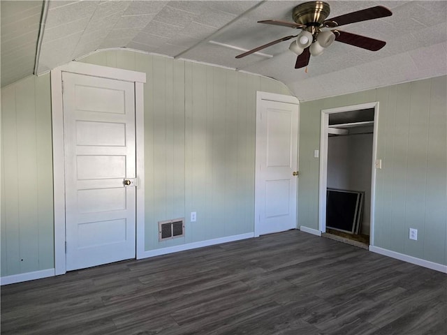 unfurnished bedroom featuring a ceiling fan, vaulted ceiling, dark wood-style floors, and visible vents