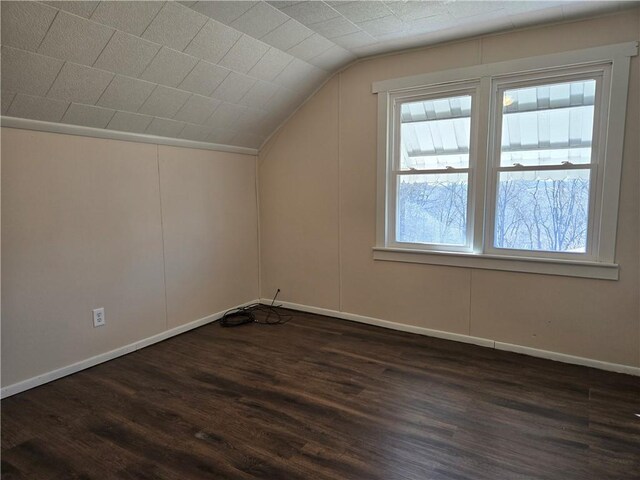 additional living space featuring baseboards, dark wood-style floors, and vaulted ceiling