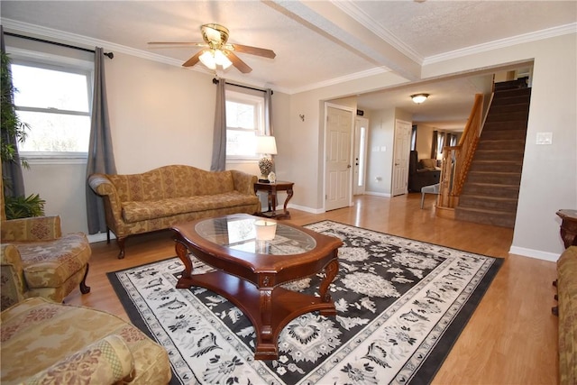 living room featuring a wealth of natural light, stairway, light wood-style flooring, and crown molding