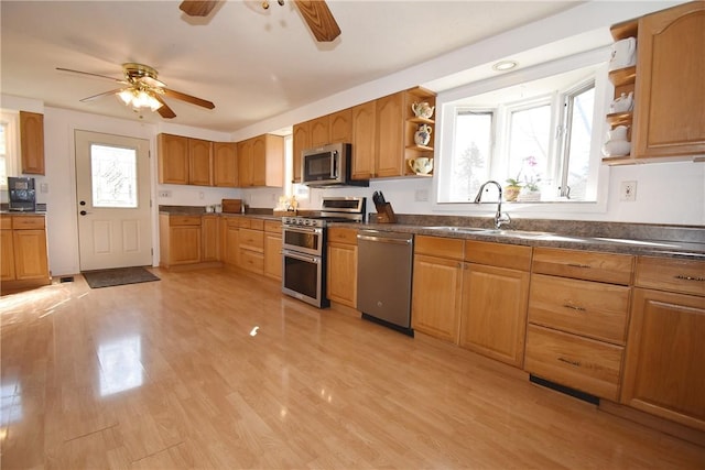 kitchen featuring a sink, open shelves, light wood finished floors, and stainless steel appliances