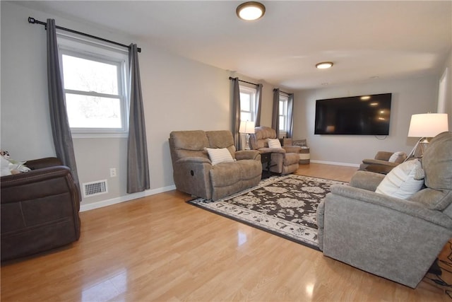 living area featuring visible vents, light wood-style flooring, and baseboards