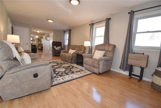 living room featuring wood finished floors, a healthy amount of sunlight, and baseboards