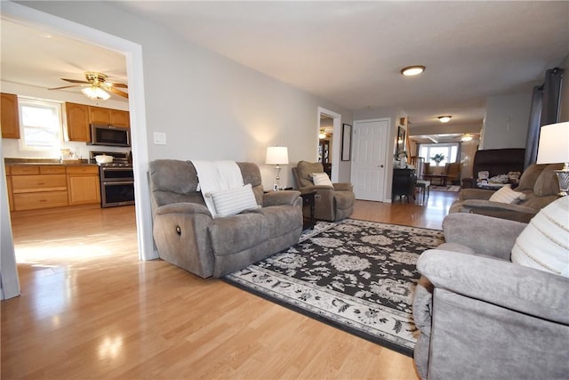 living area with light wood-type flooring and ceiling fan