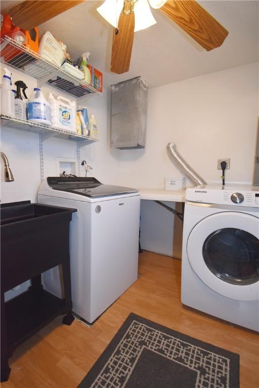 laundry room with ceiling fan, laundry area, light wood-style flooring, independent washer and dryer, and a sink