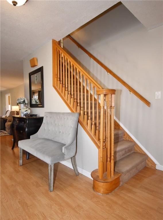 stairway featuring wood finished floors, baseboards, and a textured ceiling