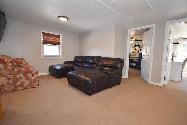 living area with baseboards, attic access, and carpet