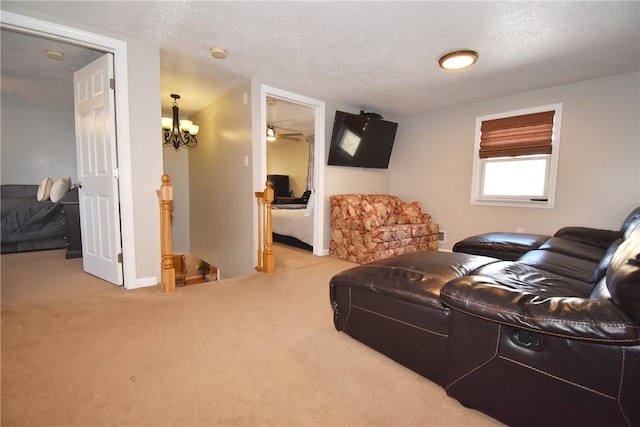 living area with a chandelier, carpet flooring, a textured ceiling, and baseboards