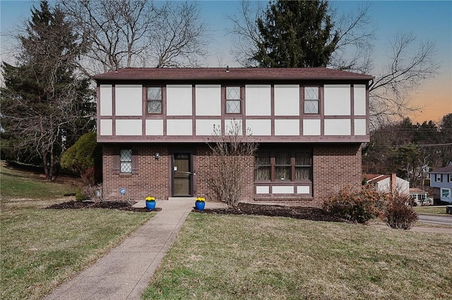 tudor house with brick siding and a front yard