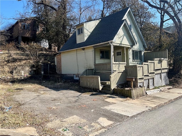 exterior space with roof with shingles and a porch