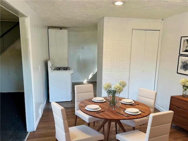 dining area with baseboards, a textured ceiling, and wood finished floors