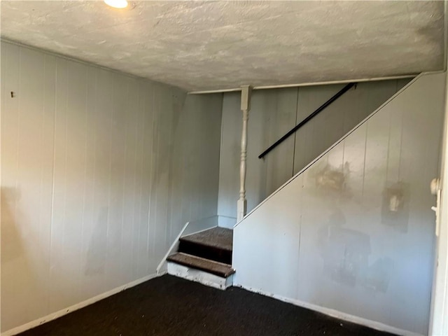 finished below grade area with stairway, baseboards, and wooden walls