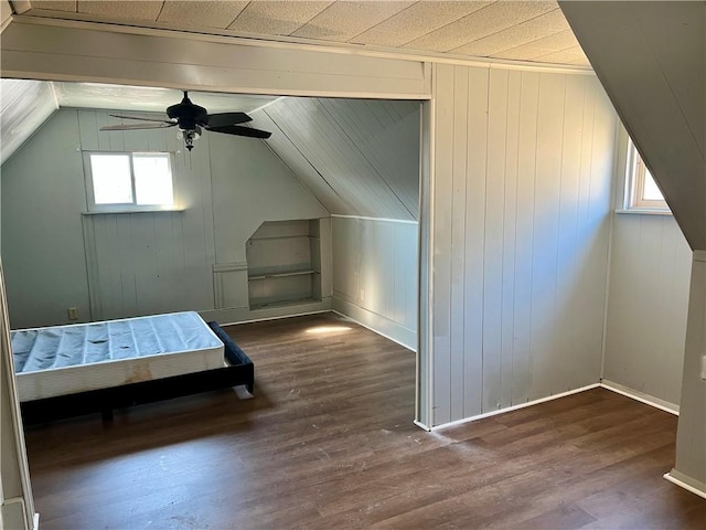 unfurnished bedroom featuring ceiling fan, baseboards, wood finished floors, and vaulted ceiling