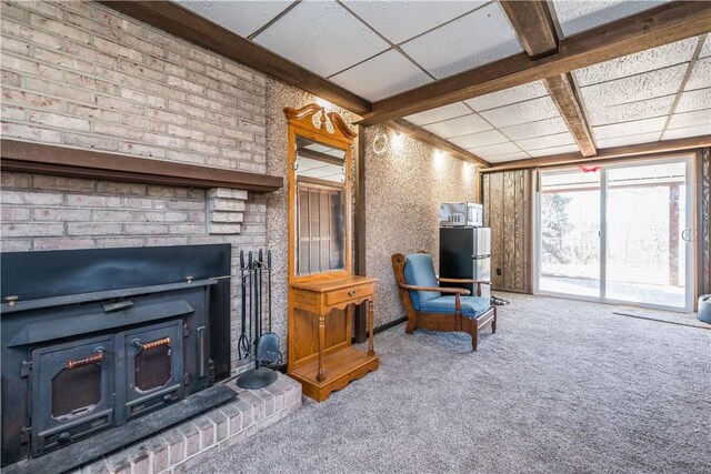 carpeted living area featuring beamed ceiling, a fireplace, and a paneled ceiling