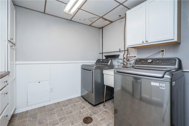 laundry room with cabinet space, wainscoting, and washing machine and clothes dryer