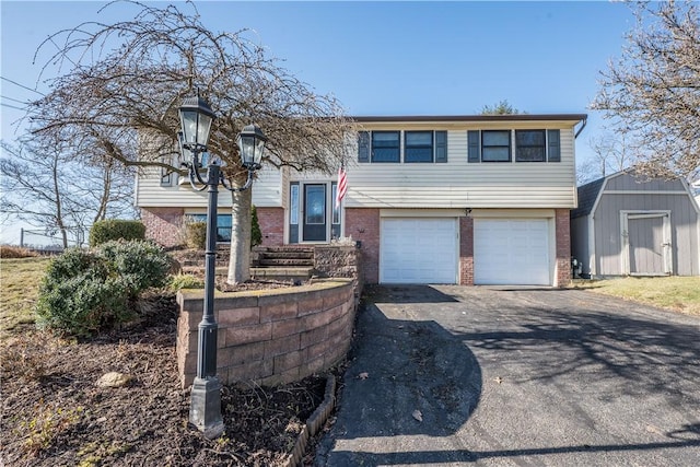 bi-level home with driveway, a garage, brick siding, and a shed