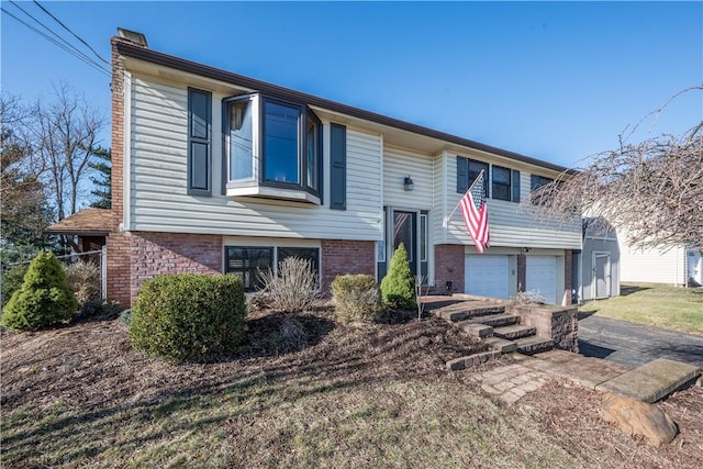 split foyer home featuring a garage, brick siding, and a chimney