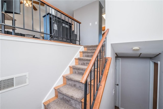 stairway with a ceiling fan, wood finished floors, and visible vents