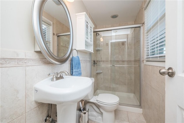 bathroom with tile patterned flooring, tile walls, toilet, and a shower stall