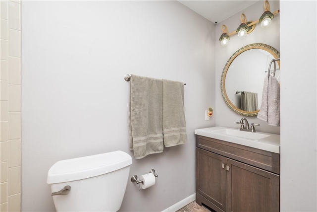 bathroom featuring baseboards, toilet, and vanity