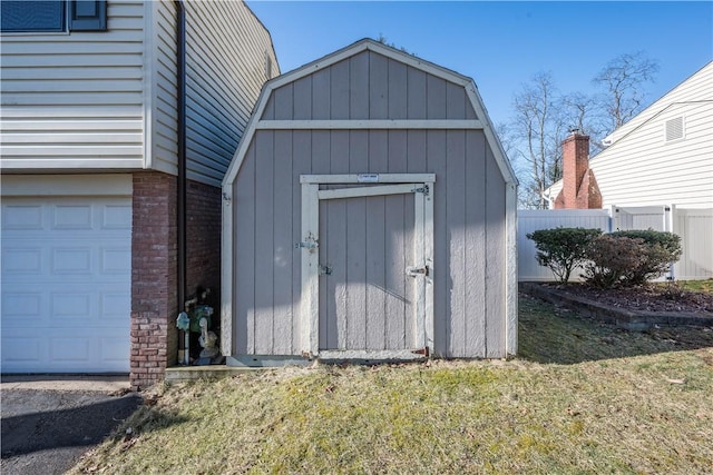 view of shed featuring fence and a garage