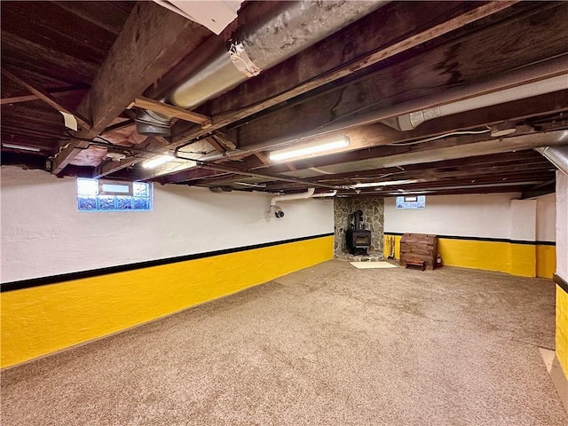 basement with a wood stove and carpet floors