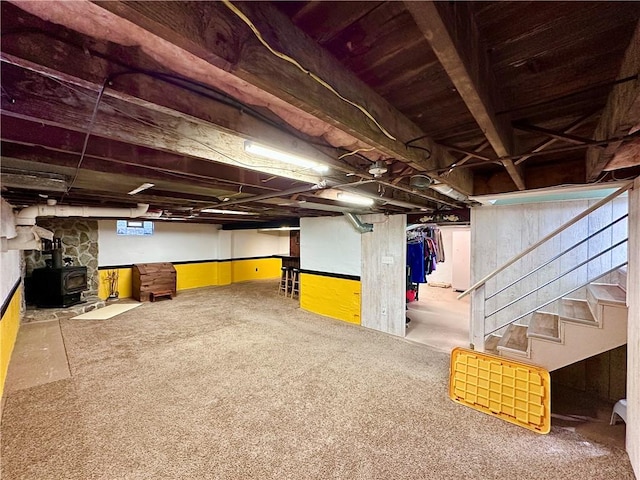 basement with stairway, carpet flooring, and a wood stove