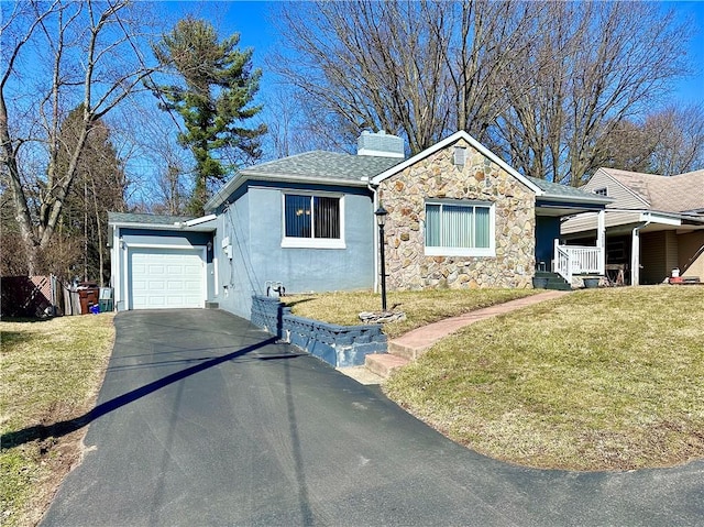 view of front of house featuring driveway, a front lawn, stone siding, a garage, and a chimney