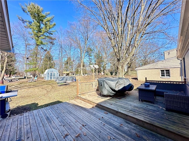 wooden terrace featuring a storage unit, an outdoor hangout area, an outdoor structure, and grilling area