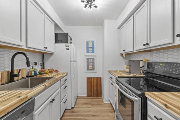 8179 Ohio River Blvd Unit 32, Emsworth, PA 15202 - kitchen featuring light wood-type flooring, butcher block countertops, a sink, appliances with stainless steel finishes, and decorative backsplash