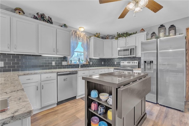 kitchen featuring light wood finished floors, decorative backsplash, white cabinets, and appliances with stainless steel finishes