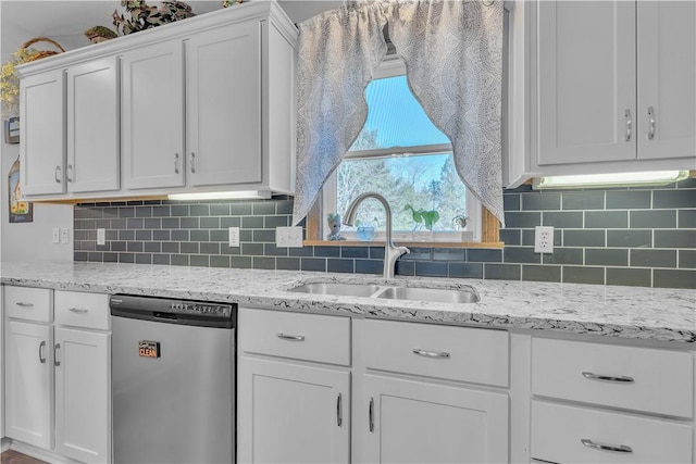 kitchen with a sink, backsplash, stainless steel dishwasher, white cabinets, and light stone countertops