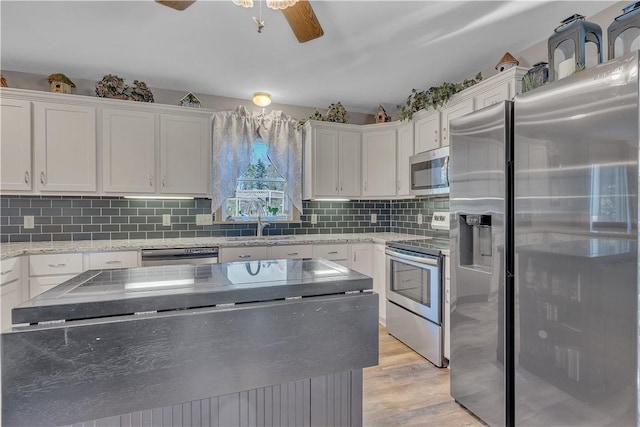 kitchen featuring a sink, tasteful backsplash, white cabinetry, appliances with stainless steel finishes, and light wood finished floors