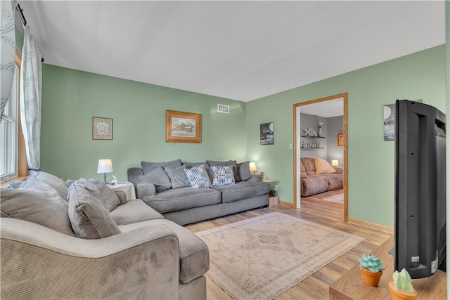 living room featuring wood finished floors, visible vents, and baseboards