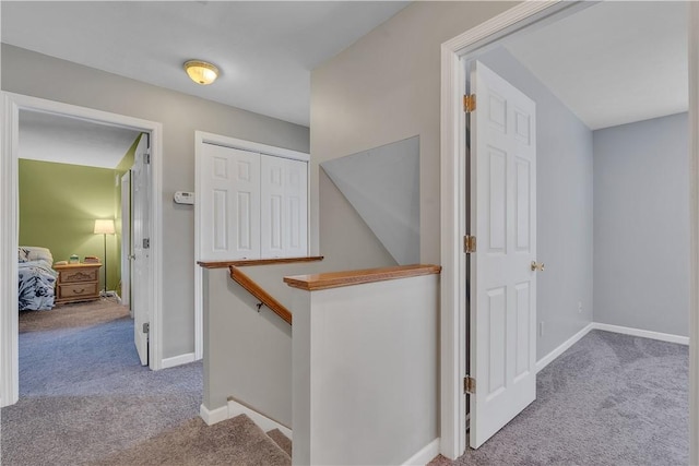 corridor featuring an upstairs landing, baseboards, and carpet floors