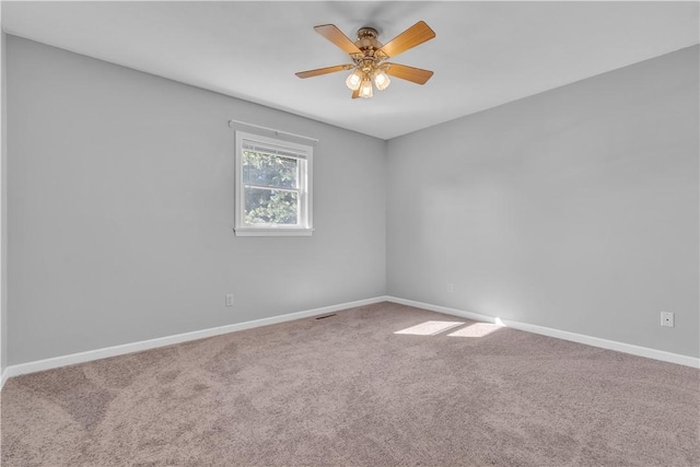 carpeted spare room with a ceiling fan and baseboards