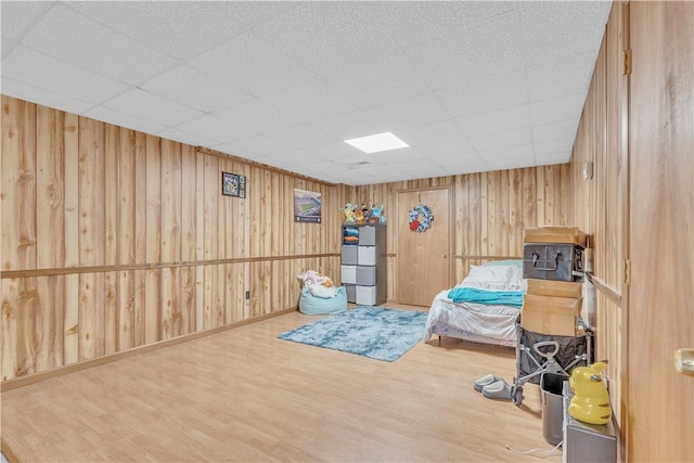 bedroom with fridge, wood finished floors, wood walls, and a paneled ceiling