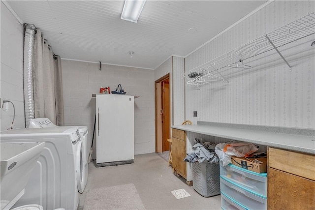 washroom with concrete block wall, washing machine and dryer, and laundry area