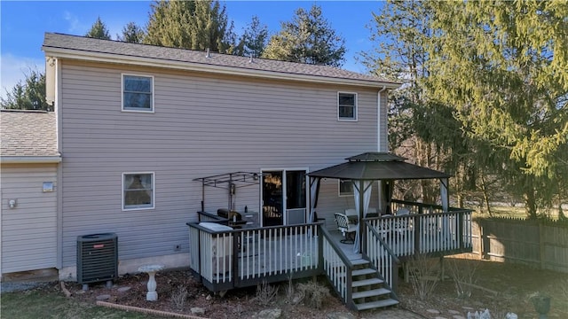 back of property with a deck, central air condition unit, and roof with shingles