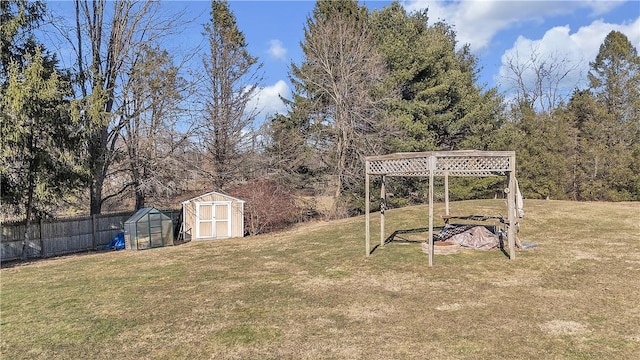 view of yard featuring a greenhouse, an outbuilding, a storage shed, and fence