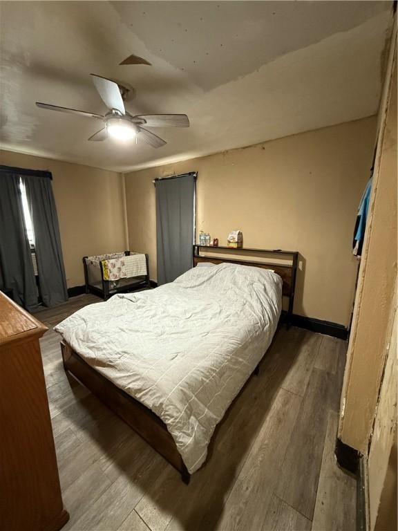 bedroom with a ceiling fan, wood finished floors, and baseboards