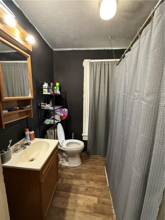 bathroom featuring vanity, toilet, wood finished floors, and a textured ceiling