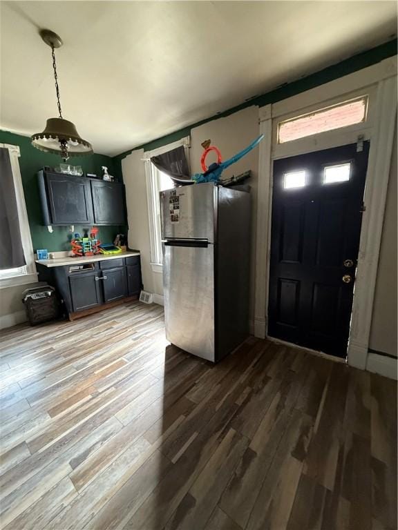 kitchen featuring light countertops, wood finished floors, freestanding refrigerator, and pendant lighting