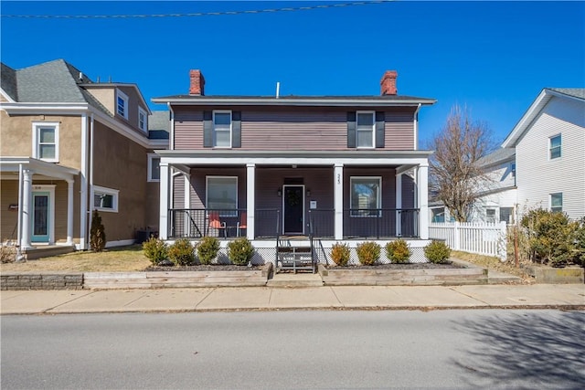 view of front of home featuring a porch, a chimney, and fence